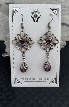 Victorian vintage style earrings in 3 colours. The square filagree and the bead caps are silver plated and made in USA, (see below for more info). They measures 19 mm across and each one has a coloured centre stone. On each earring the total drop, measured from the top of the stainless steel Fish hook is 60mm or 2 ½ inches. CLEAR STONE EARRING This earring has a clear Czech faceted bead as the drop with a small clear Swarovski  bead. PURPLE STONE EARRING This earring has a Czech faceted bead in Vintage Style Earrings, Victorian Vintage, Swarovski Beads, Silver Plated Jewelry, Purple Stones, Best Friend Gift, Bridal Jewellery, Birthday Gift For Her, Stainless Steel Earrings