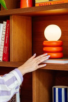 a person reaching for an orange object on a book shelf