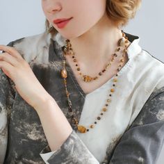 This natural stone necklace combines raw stones of different materials and shapes, creating a simple and natural original ecology with a touch of Zen aesthetics. The beautiful earth-tone design is perfect for all seasons and can be worn alone or stacked with a white fossil necklace for a stunning look. Embrace the beauty of nature with Planet Trail. Metal: 18K Recycled Gold Plated On Brass Gemstone: Tiger's Eye,Tea Crystal,Picture Stone,Other Natural Stone Length: 1040-1090mm Weight: 38g Fossil Necklace, Coffee Caramel, Natural Stone Necklace, Edison Pearls, Natural Stones Necklace, Gemstone Beaded Necklace, Long Beaded Necklace, Tiger Eye Stone, Unique Coffee