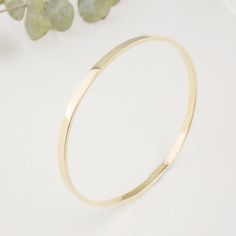 "Introducing our exquisite Solid 14K Gold Bangle, meticulously forged into a flawless round shape, this bangle epitomizes the artistry of skilled goldsmiths. Crafted from solid 14k gold, its solid construction ensures enduring beauty and resilience. Its robust 3mm width and 1.5mm thickness distinguishes it from more delicate alternatives. The lustrous surface reflects the unparalleled quality of the material, making it a luxurious addition to any jewelry collection. Each bangle will be made to order for you. Please enter your hand circumference. Bangle width: 3mm Bangle thickess: 1.5mm Bangle inside diameter: 6.5mm(2.5\") -measuring 19cm size" 14k Gold Bangle With Shiny Finish, Polished Hoop Bangle As A Gift, Yellow Gold Shiny Finish Cuff Bracelet, Adjustable 14k Gold Bangle With Polished Finish, Polished 14k Gold Cuff Bracelet, Modern 14k Gold Bracelets With Shiny Finish, 14k Gold Cuff Bracelet With Polished Finish, 14k Gold Polished Cuff Bracelet, 14k Gold Polished Finish Cuff Bracelet