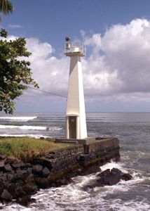 a light house sitting on top of a rocky shore next to the ocean with waves coming in