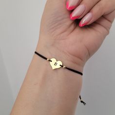 a woman's hand holding onto a black string bracelet with two hearts on it