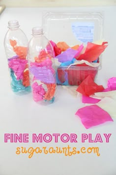 some plastic bottles filled with different colored tissue paper and other crafting supplies on a table