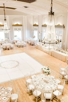 an elegant ballroom with chandeliers and tables set up for a formal function in white