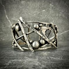 "This hand-forged 925 solid Sterling silver bangle-style cuff, \"Sticks & Stones\" is not only a unique design, it is truly made from scratch and one-of-a-kind.   Weight:  88.38 grams! For reference, the model in the vid has a 6.5\" wrist, wearing a 6\" adjustable cuff.  This bracelet comes in a Silver Fig gift box." Unique Oxidized Metal Cuff Bracelet, Unique Metal Cuff Bracelet With Oxidized Finish, Unique Adjustable Sterling Silver Bracelet, Sterling Silver Cuff Bracelet Hand Cast Bangle, Unique Adjustable Bracelet With Oxidized Finish, Unique Oxidized Cuff Bracelet Bangle, Unique Oxidized Finish Cuff Bangle, Unique Adjustable Oxidized Cuff Bracelet, Adjustable Artistic Sterling Silver Bracelets