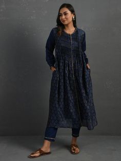 A gold hand block printed front open chanderi kurta with pintucks, gota details, full-length sleeves with gathers. This indigo kurta comes with a separate matching mul slip and pants with elasticated and drawstring adjustable waistband Kurta measurements (in Inches): Size S: Bust - 39", Waist - 39" Size M: Bust - 42", Waist - 42" Size L: Bust - 45", Waist - 45" Length: 47", Sleeve length: 21" Pant Measurements (in Inches): Size S: Waist - 30-32" Size M: Waist - 33-35" Size L: Waist - 36-38" Leng Indigo Cutdana Kurta For Eid, Indigo Designer Straight Kurta, Designer Indigo Straight Kurta, Indigo Designer Wear Straight Kurta, Blue Long Sleeve Kurta With Gota Work, Elegant Long Sleeve Sets With Pintucks, Indigo Chikankari Embroidery Kurta For Navratri, Indigo Chikankari Kurta For Navratri, Indigo Salwar Kameez With Chikankari Embroidery