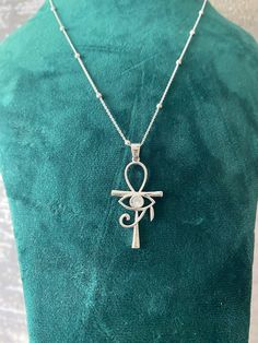 This elegant necklace features a stunning pendant combining two of the most iconic symbols of ancient Egypt: the Ankh and the Eye of Horus. Crafted from high-quality sterling silver, the pendant showcases an intricate design that includes the Eye of Horus set within the loop of the Ankh. The necklace is complemented by a delicate chain adorned with small, evenly spaced beads, adding a touch of sophistication to this unique piece. Perfect for anyone interested in Egyptian mythology or looking for Spiritual Ankh Necklace Hallmarked, Artistic Engraved Sterling Silver Necklaces, Eye Of Horus Jewelry, Artistic Engraved Sterling Silver Necklace, Symbolic Silver Necklaces With Adjustable Size, Sterling Silver Symbolic Pendant Necklace, Adjustable Silver Symbolic Necklace, Symbolic Sterling Silver Pendant Necklace, Nickel-free Symbolic Sterling Silver Necklace