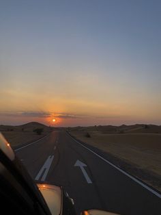 the sun is setting on an empty road in the middle of nowhere, as seen from inside a car