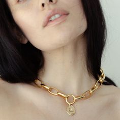 a close up of a woman wearing a gold chain necklace with a heart charm on it