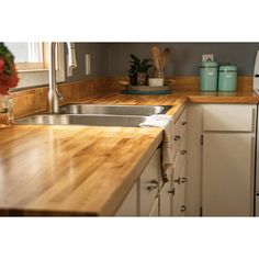 a kitchen with wooden counter tops and white cabinets