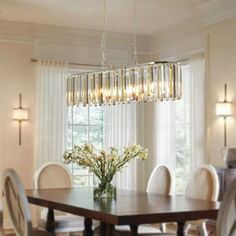 a chandelier hanging over a dining room table with chairs and flowers in the center