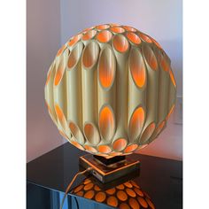 a lamp that is sitting on top of a table next to a glass container with orange dots