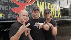 two men and a woman standing in front of a tour bus giving the peace sign