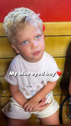 a little boy sitting on top of a wooden bench