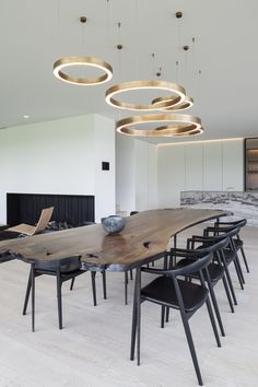 a large wooden table surrounded by chairs in a room with lights hanging from the ceiling