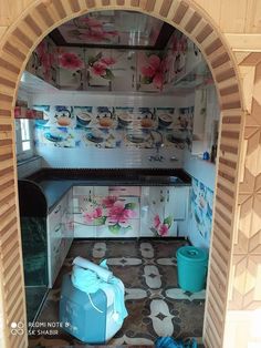 the inside of a doll house kitchen with pink flowers on the wall and blue trash can