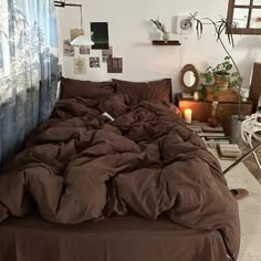 an unmade bed with brown sheets and pillows in a bedroom next to a window