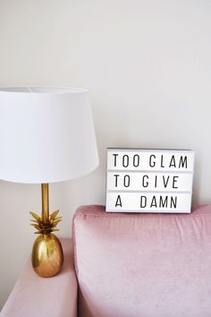 a light box that says too glam to give a damn sitting on a pink couch