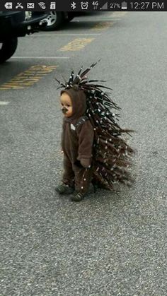 a baby dressed up in a costume with spikes on it's head is walking down the street