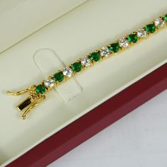 YELLOW GOLD FINISH Created Diamond Round Cut Green Emerald Tennis Bracelet  This green emerald and created diamond bracelet is made in the style of a tennis bracelet with a circular fine finish, with created green emerald gems. It is a bracelet sure to provide you with style comfort. The green emerald gems are studded with small diamanté's carved to perfection, offering a great sheen and pristine look.  Round diamonds are traditionally the first and most popular diamond that's given as a symbol of commitment. They have a classic uniform and symmetrical shape that consists of 58 facets, which qualifies them a brilliant cut. The faceting on round cut diamonds also makes colour and inclusions appear better than in other fancy shapes. In fact, these stones are so beloved that over 50% of all d Elegant Cubic Zirconia Bracelet For Her, Luxury Green Tennis Bracelet For Formal Events, Luxury Green Round Cut Jewelry, Luxury Emerald Tennis Bracelet Gift, Gemstone Tennis Bracelet Gift, Luxury Bracelet As Gift, Green Formal Bracelet Jewelry, Exquisite Gold Tennis Bracelet As Gift, Classic Gemstone Tennis Bracelet Gift