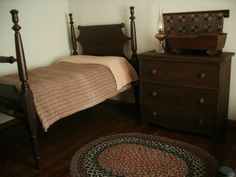 a bed sitting next to a wooden dresser on top of a hard wood floor