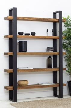 a wooden shelf with black metal legs and shelves on the wall, in front of a potted plant