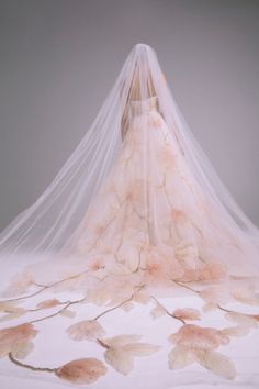 a wedding dress with flowers on it and a veil hanging over the back of it