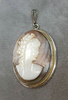 Hallmarked 800 silver Mother of Pearl cameo pendant. The cameo pendant measures approximately 1 1/2 inches x 1 inch. The necklace chain attached to the cameo pendant is sold separately. Other necklace styles are also available. The cameo pendant is in very good condition. The cameo pendant is circa 1940. The cameo pendant comes in a quality gift box. Silver Cameo Round Pendant Jewelry, Silver Cameo Jewelry With Round Pendant, Collectible Cameo Jewelry With Round Pendant, Round Silver Cameo Necklace, Collectible Cameo Round Pendant Jewelry, Cameo Medallion Jewelry For Anniversary, Silver Cameo Medallion Necklace, Silver Cameo Oval Pendant Jewelry, Victorian Cameo Silver Necklace