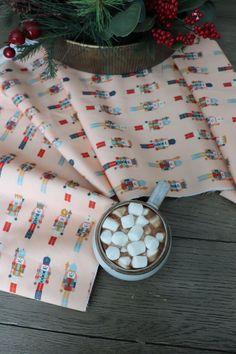 hot chocolate and marshmallows in a mug on a table next to christmas decorations