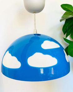 a blue and white mushroom shaped light hanging from a ceiling fixture next to a potted plant