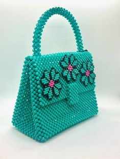 You'll feel lucky to have this bag from Del Duca. Handmade in Argentina, this beaded bag boasts a vibrant green color and three flowers with pink accents along the top flap. This chic bag comes with a red insert to ensure all your goods stay safe. Plastic beads 8.25" L x 4.25" W x 11" H Handmade Green Top Handle Shoulder Bag, Handmade Green Rectangular Bag, Green Beaded Pouch Shoulder Bag, Green Beaded Bags For Daily Use, Green Flower-shaped Shoulder Bag For Daily Use, Green Flower Shaped Shoulder Bag For Daily Use, Green Beaded Shoulder Bag For Daily Use, Green Floral Shoulder Bag For Daily Use, Green Top Handle Bags As Gifts