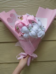 a person is holding a bouquet of flowers in pink paper on a wooden wall background