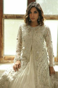 a woman in a white dress sitting on a window sill next to a window