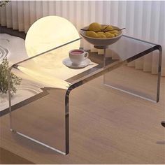 a glass table with a bowl of fruit on it and a plate of food in the background