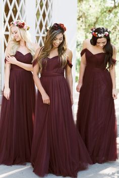 three bridesmaids in long dresses with flower crowns on their heads