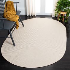 a white rug with a chair and potted plant on the floor next to it