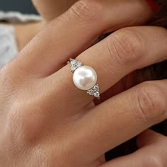 a woman's hand with a pearl and diamond ring