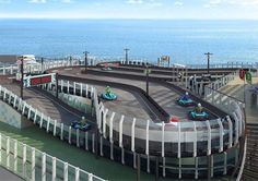 people are riding karts on the track by the water