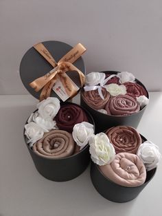 three round boxes filled with different types of fabric flowers and ribbons on top of each other