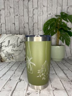 a green tumbler sitting next to a potted plant