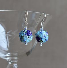 These Dark and Light Blue Raised Floral Lampwork Glass Bead with Crystal earrings are great for every day or an evening out!   An excellent Mother's Day Gift, Birthday Gift, Holiday or anytime earring!   The earrings have a 1 1/2" drop, and Sterling Silver ear wires.  The floral glass bead is approximately 1/2" (15mm)  in diameter.  The raised blue glass flowers (with a tiny pink or blue center and green leafs) are on a lampwork glass bead with a black core. The blue crystals are 2 mm.   The earring comes with sterling silver earwires. However, If you need Niobium ear wires for allergy purposes, please send a message to me with your order/payment. Niobium wire offers outstanding qualities, including being non-reactive with those who have sensitive skin or metal allergies.  The niobium earw Blue Flower-shaped Earrings With Ear Wire, Adjustable Flower Shaped Blue Beaded Earrings, Adjustable Blue Flower Beaded Earrings, Blue Flower Beaded Earrings For Gift, Blue Round Flower Earrings Hypoallergenic, Blue Flower Earrings For Jewelry Making, Blue Round Hypoallergenic Flower Earrings, Hypoallergenic Blue Flower Earrings, Blue Wire Wrapped Beaded Earrings