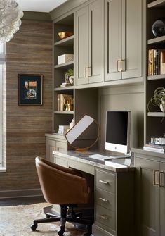 a desk with a computer on top of it in front of a book shelf and cabinets