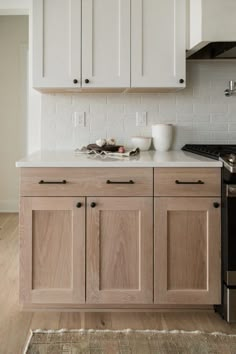 a kitchen with white cabinets and wood floors