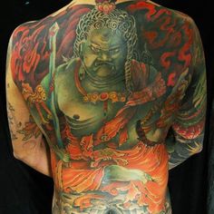 the back of a man's body with tattoos on it and an image of a buddha