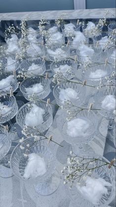 many clear bowls with small white flowers in them on a gray tablecloth covered surface