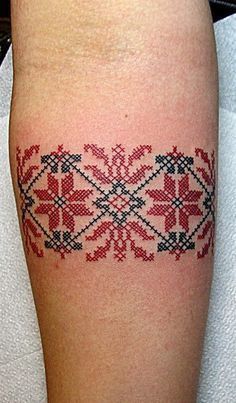 a woman's leg with a red and black cross stitched design on it