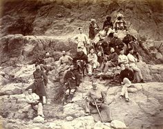 a group of men sitting on top of a rocky hill next to eachother