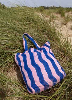 The oversized, multi-use Wave Tote is stylish enough to compliment any outfit and sturdy enough to carry your laptop, farmer's market finds, or beachside essentials. Crafted from 100% cotton canvas and hand block printed in bright pink and ocean blue by artisans in India, every tote is unique. Blue Canvas Bag For The Beach, Pink Canvas Beach Bag For Summer, Summer Pink Canvas Beach Bag, Blue Cotton Beach Bag For Vacation, Blue Cotton Beach Bag For Summer, Pink Canvas Bag For Beach Travel, Pink Canvas Beach Bag, Pink Cotton Beach Bag For Daily Use, Blue Cotton Canvas Bag For Vacation