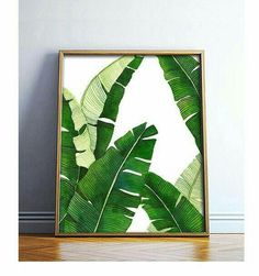 a frame with a banana leaf print on it next to a plant in a room