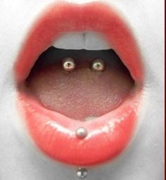 a woman's mouth with two piercings on it